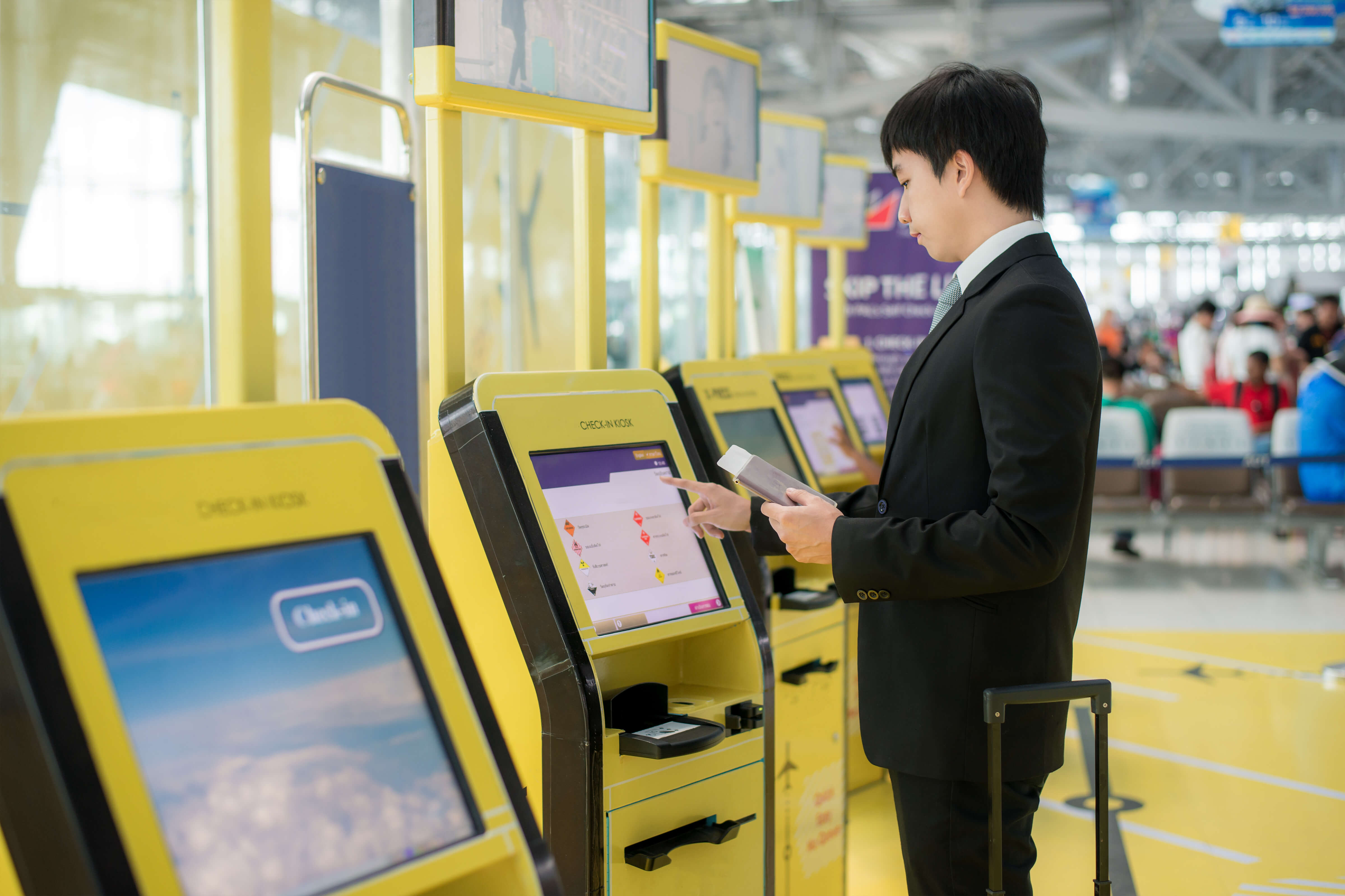 Self service airport check in kiosk with man holding passport