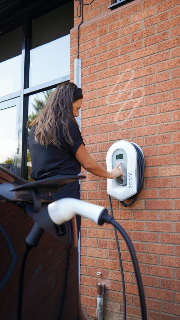 Woman plugging in her electric vehicle at work